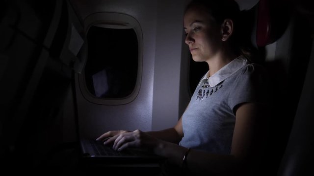 Businesswoman work on notebook in airliner, night flight