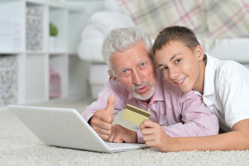 Grandfather and grandson lying on floor and using laptop, grands