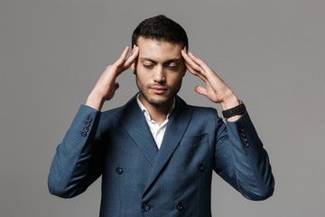 Sad tired business man with headache posing isolated over grey wall background.
