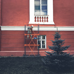 Worker painting facade of old building house, reconstruction and repair