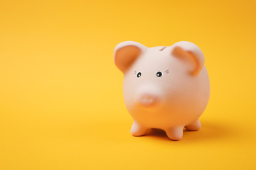 Close up photo of pink piggy money bank isolated on bright yellow wall background. Money accumulation, investment, banking or business services, wealth concept. Copy space advertising mock up.