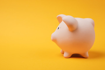 Close up photo side view of pink piggy money bank isolated on bright yellow wall background. Money accumulation investment banking or business services, wealth concept. Copy space advertising mock up.
