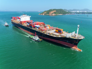 Aerial view Tug boats drag container ship to sea port for unload container to container warehouse for logistics import export, shipping or transportation concept.