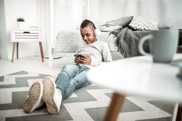 Favourite music. Joyful nice boy wearing headphones while listening to music