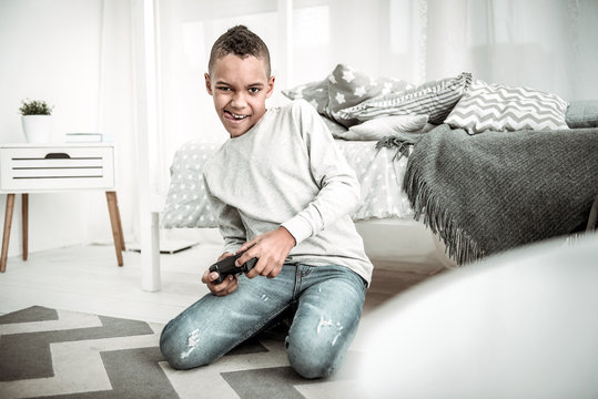 Video games. Cheerful happy boy holding a game console while playing video games