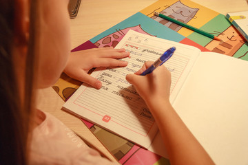 girl holding a pencil and writing in a notebook words and letters