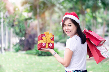 Asian Women holding gift and the bags shopping with wear earrings in christmas day celebrate.