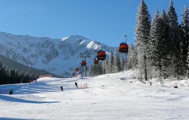 Fotobehang Cableway cabins and skiers on a sunny day on the slopes of the Jasna ski resort. © dragunoff