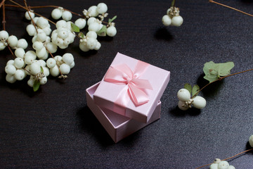 Wrapping presents. Gift boxes. Nearby there is a branch from a bush with autumn fruits of white color. Against a dark background.