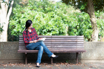 Fototapeta premium 公園のベンチで本を読む女性