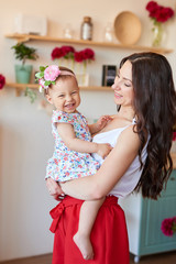 Family mother and daughter with peonies flowers in kitchen at home. Happy mother and baby daughter. Happy family. Greeting card for mother's day, for March 8, Women's Day. Birthday greetings template