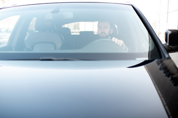 Businessman driving a luxury car, view from the outside through the windshield with copy space