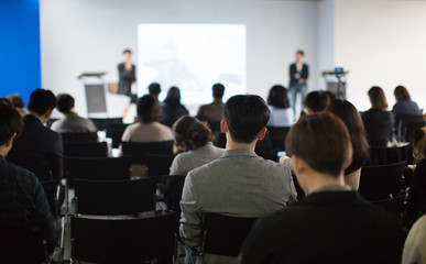 "Audience Watching a Presentation. Blurred Presenters at Conference Meeting Event. Executive Manager Speaker on Stage at Tech Business Seminar. Lecturers Presenting Training Material During Speech."