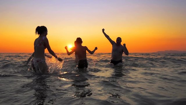 Family people are having a party dancing, spraing and jumping on the summer beach sunset, cinematic SLOW MOTION