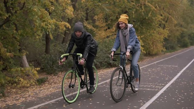 Two bicycle. Couple on bikes. Romantic biking in the autumn city park. Man and woman riding bikes. Active friends leisure. Slow motion