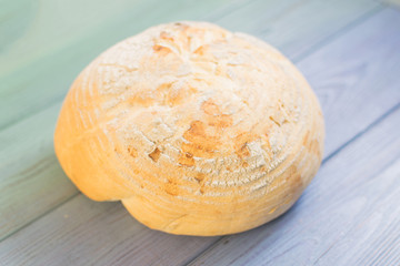 Round white bread on color wooden background.