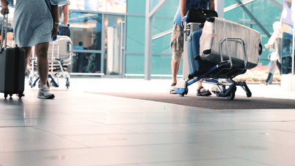 Obraz premium Close up of feet of unrecognizable people with baggages walking in terminal airport