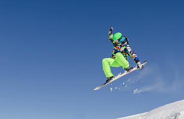 Snowboard jumping at sunny day in high mountains