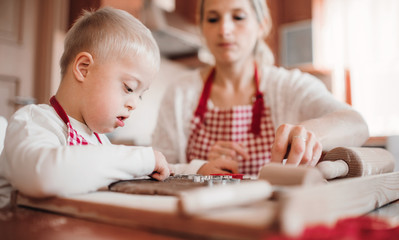 A handicapped down syndrome boy with his mother indoors baking.
