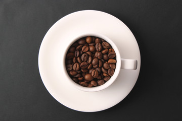  coffee beans in a cup on a dark background, top view.