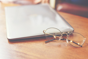 Laptop with glasses put on the wooden table for outside working and co-working space.