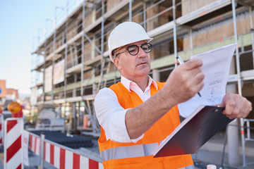 Mann, Arbeiter auf Baustelle mit Plan in der Hand