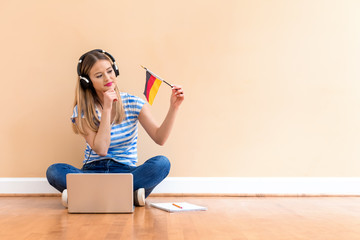 Young woman with Germany flag using a laptop computer against a big interior wall