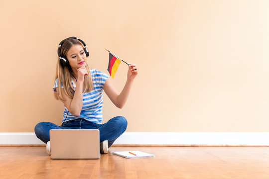 Young woman with Germany flag using a laptop computer against a big interior wall