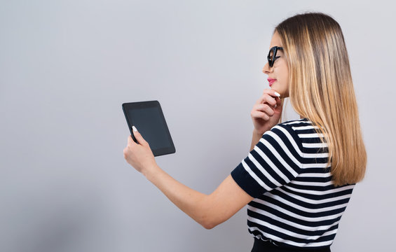 Young woman with a tablet computer on a gray background