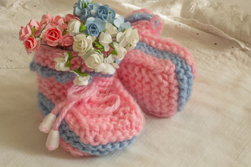 Fototapeta na wymiar Beautiful tender photo for newborn albums. Gently pink booties in flowers.