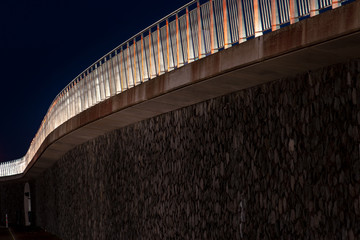 Featured architecture at night with blue light and a white iron railing.