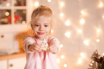 Fototapeta na wymiar Smiling baby girlholding gingerbread cookie closeup. Winter holidays. Christmas season.
