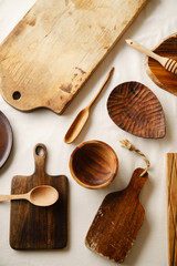 Various wooden tableware. Cutting boards, spoons of different forms, plate and bowl on linen tablecloth
