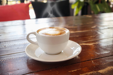 heart shape latte art in white coffee cup on wood table in cafe restaurant