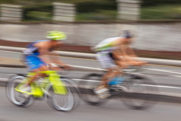 Blurred silhouettes of moving cyclists on a blurred background of the city