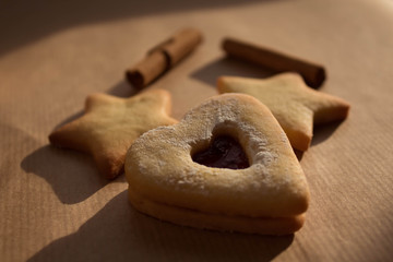 the Сhristmas cookies and cinnamon sticks are on the paper background. Christmas background. Close...