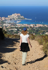 Young Women is walking a mountain path over Calvi (Corsica)