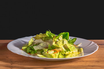 Fresh salad on white plate and wooden table for dinner