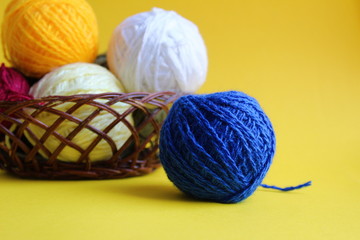 Knitting yarn in different colors on a yellow background
