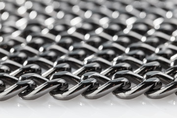 Abstract background of black decorative steel chain lying on a white background. Close-up