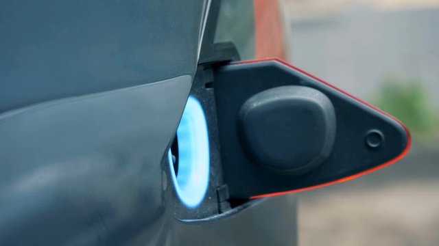 Filler hole of an electrocar opens and a fuelling nozzle is getting inserted into it
