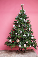 Christmas tree with beautiful ornaments on pink background