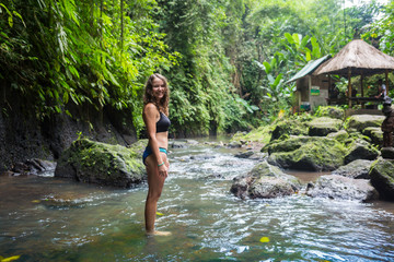 Young traveler woman in the jungle river. Rainforest of Bali island. Tourist adventure concept.