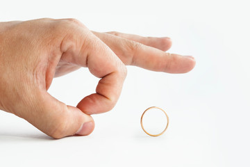 Close up of person's hand pushing away wedding golden ring isolated on white. Man makes finger kick...