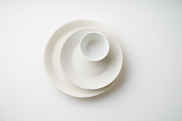 Porcelain plates of various form and size on white background. Overhead image, copy space.