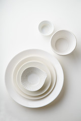 Porcelain plates of various form and size on white background. Overhead image, copy space.