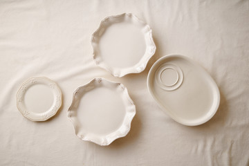 Porcelain plates on linen tablecloth. Overhead image, copy space. Natural materials concept.