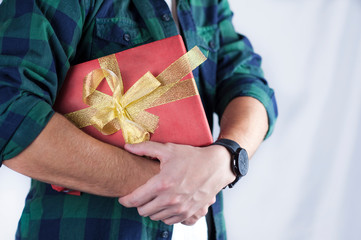 Young handsome guy holds a gift in his hands close-up