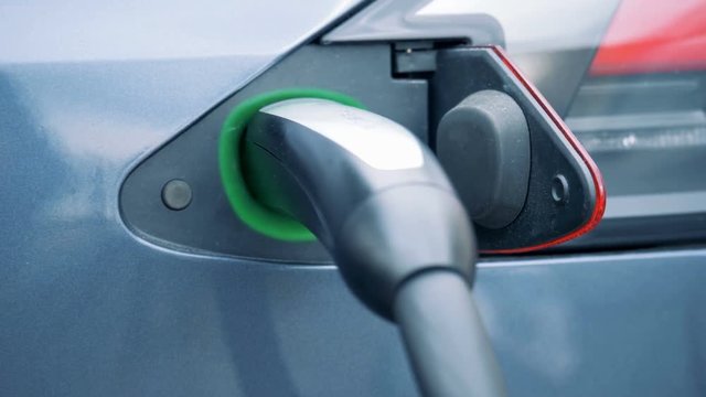 Electric-battery car is being reloaded by an inserted fuelling nozzle