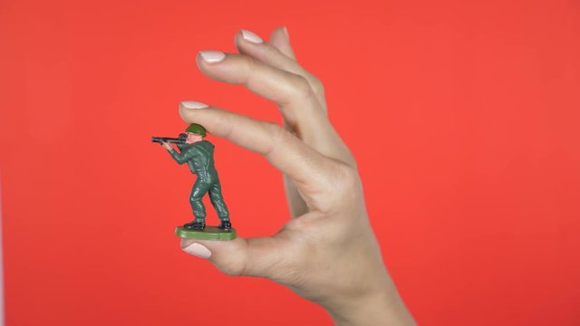 Closeup of female hand holding green plastic toy soldier.